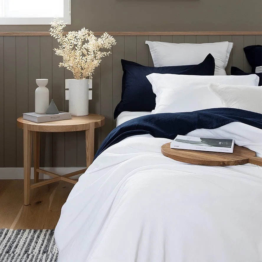 Neatly made bed with white and navy bedding in a bedroom setting.