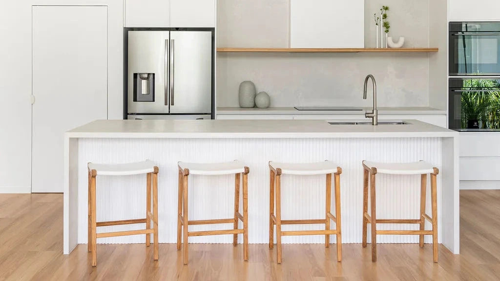 Modern kitchen with white island, bar stools, and stainless steel appliances.