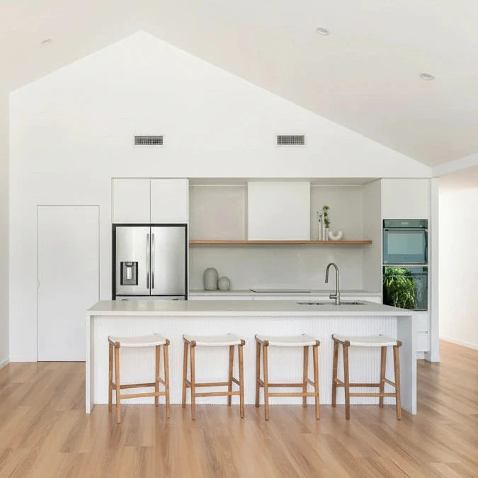 Modern kitchen with white island bench with white leather and teak counter stools