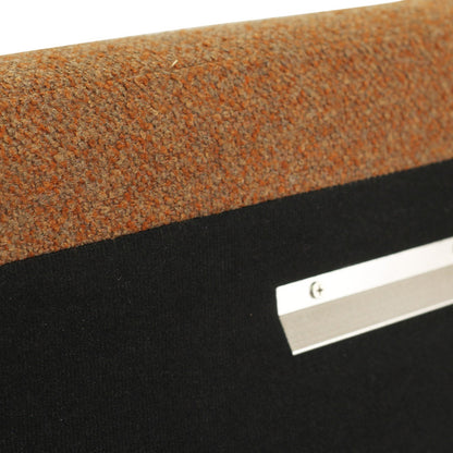 Close-up of a textured orange-brown carpeted surface above a black panel with a silver metal mounting strip.