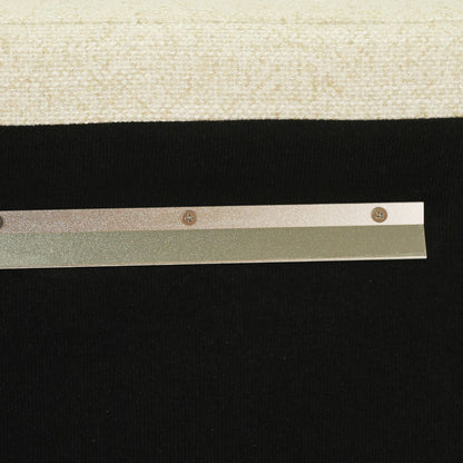 A close-up of a metallic silver strip with four small round screw-like details, positioned horizontally against a black background with a beige textured surface at the top.