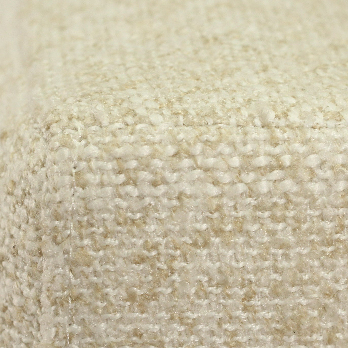 Close-up of a textured woven fabric in a warm cream or off-white color, showing the detailed knit pattern and corner seam.
