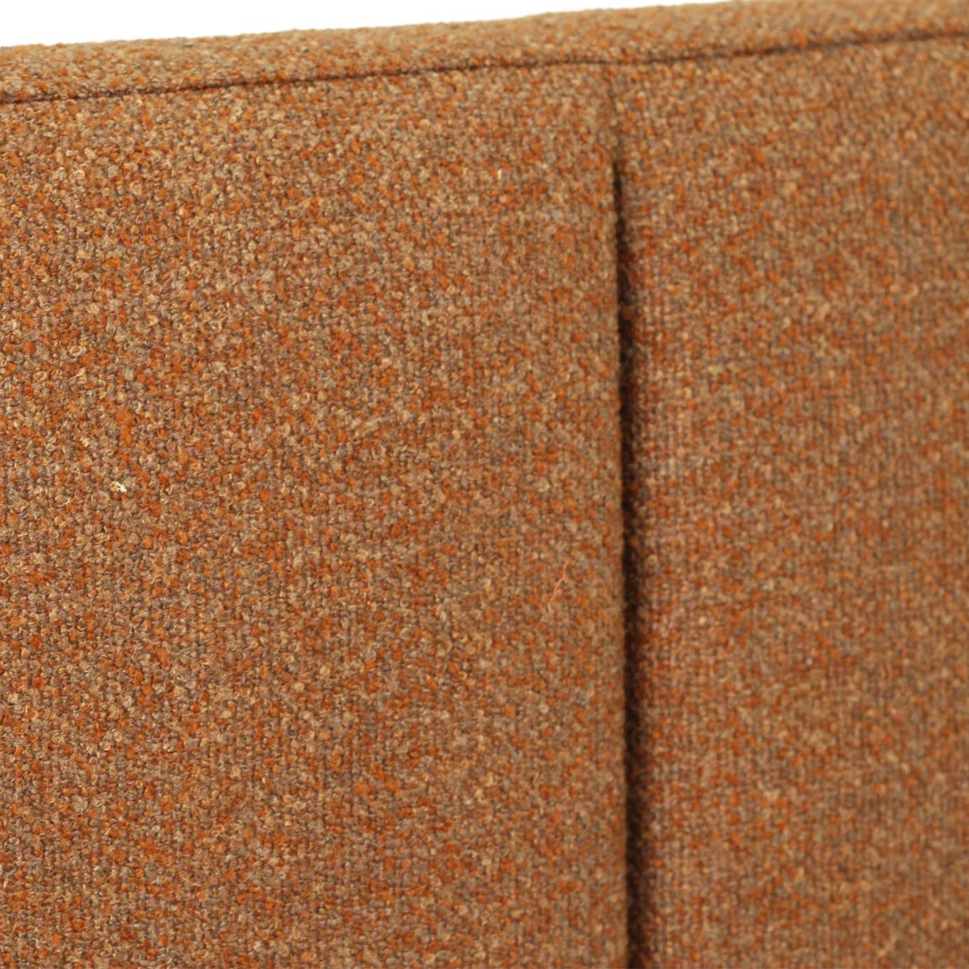 Close-up of a textured woven upholstery fabric in a warm rust-orange color, showing the weave detail and a vertical seam.