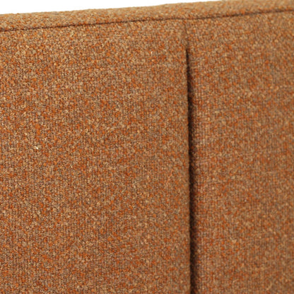 Close-up of a textured woven upholstery fabric in a warm rust-orange color, showing the weave detail and a vertical seam.