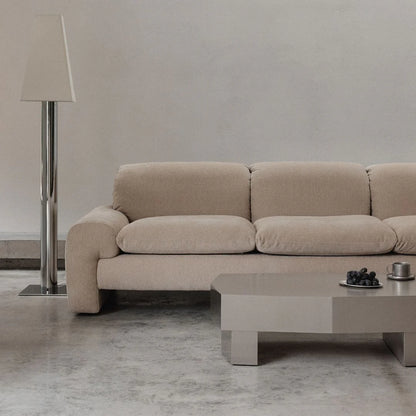 Beige sofa in a modern living room with a coffee table and floor lamp.
