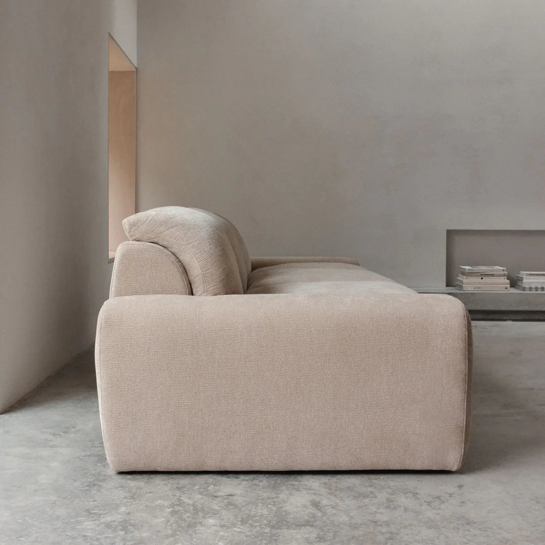 Beige sofa in a minimalistic room with gray walls and floor.