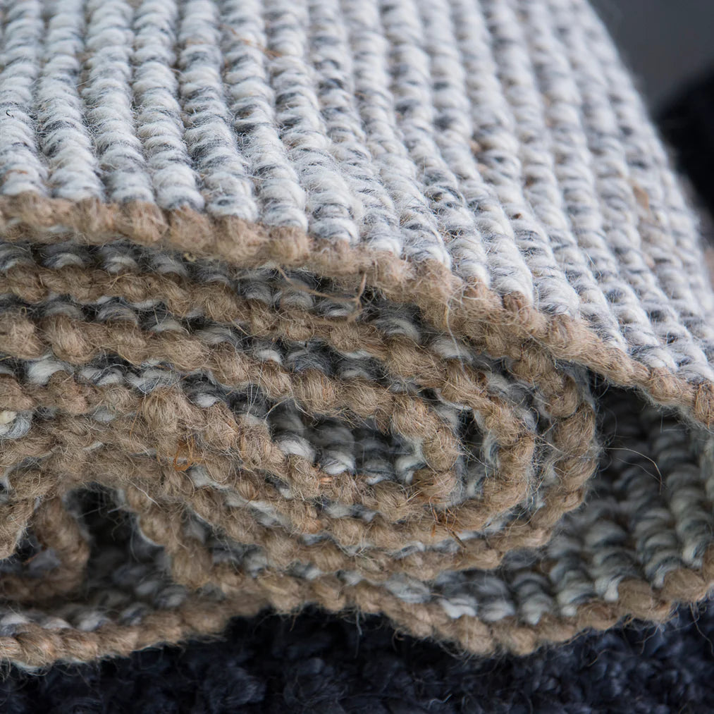 Close-up of textured rugs in beige, gray, and black.