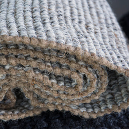 Close-up of textured rugs in beige, gray, and black.