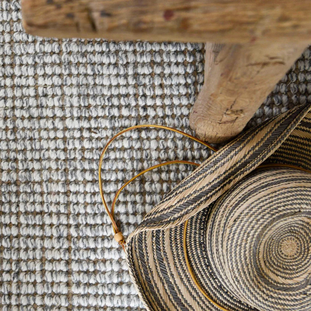 Woven bag with a wooden bench on a textured rug