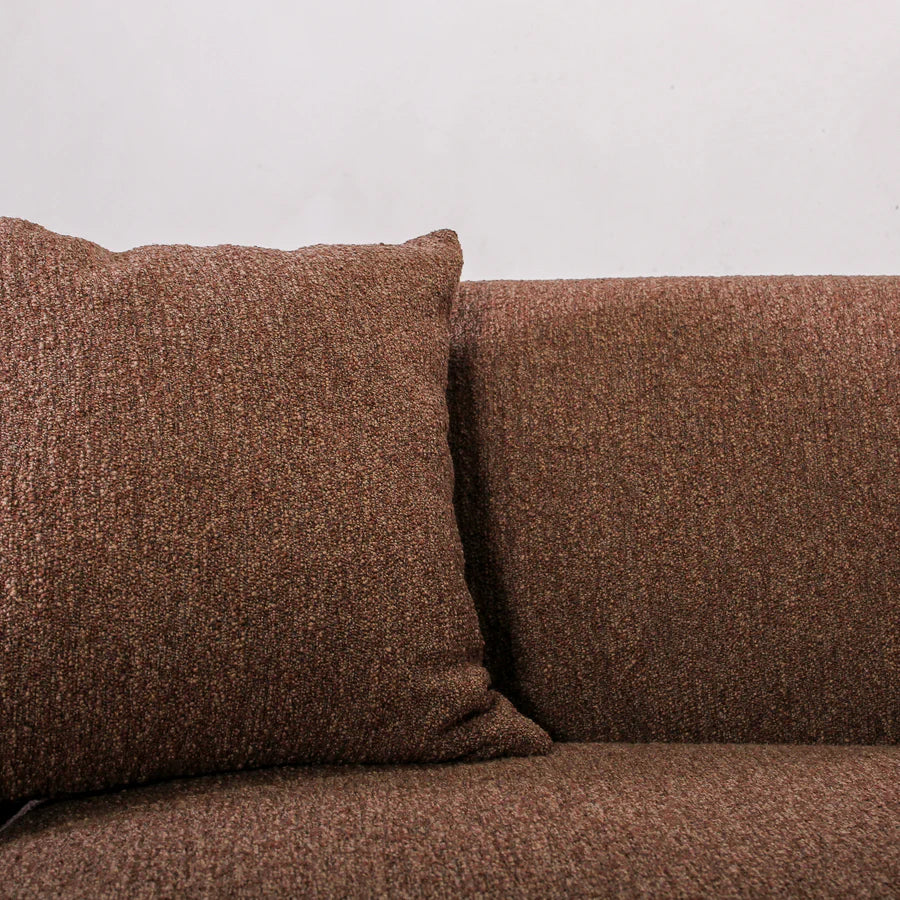 Brown textured sofa with a pillow against a light gray background