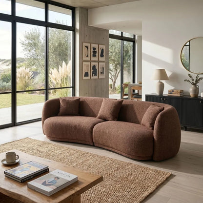 Modern living room with a brown sofa, wooden coffee table, and large windows.