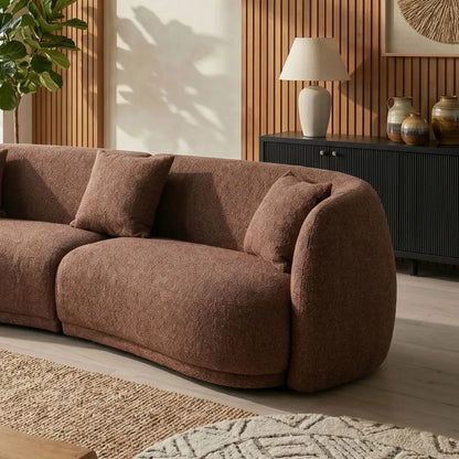 Brown sofa in a living room with a lamp and decorative items on a sideboard.