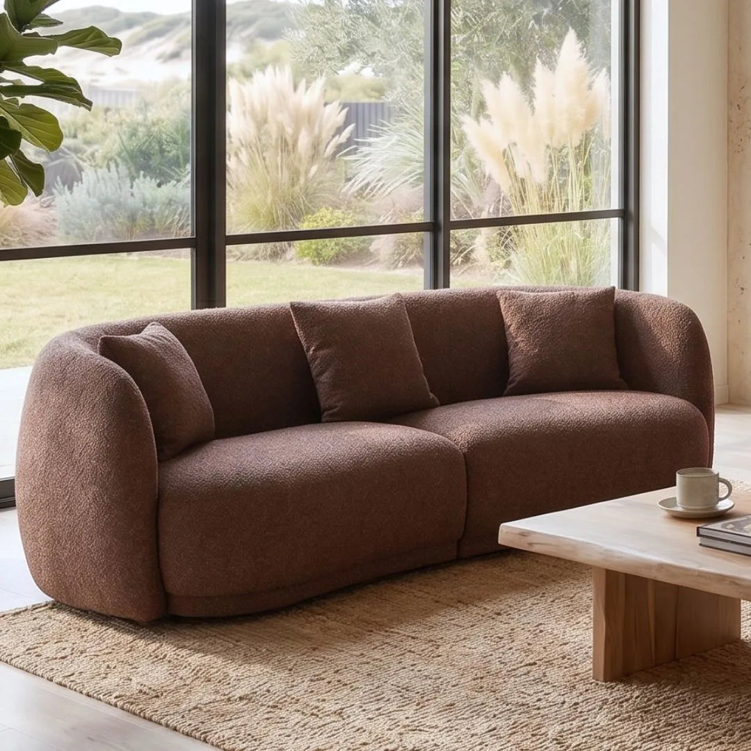 Brown sofa in a living room with large windows and outdoor view