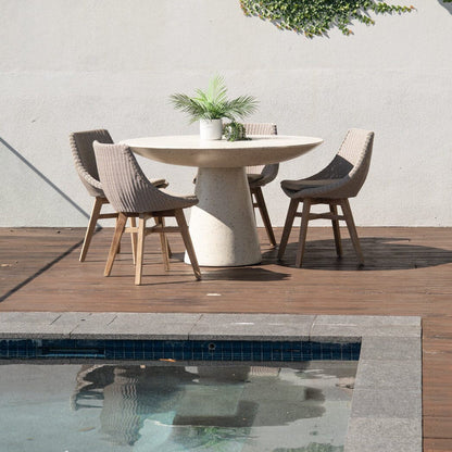 Outdoor dining area with a round table and chairs near a pool.