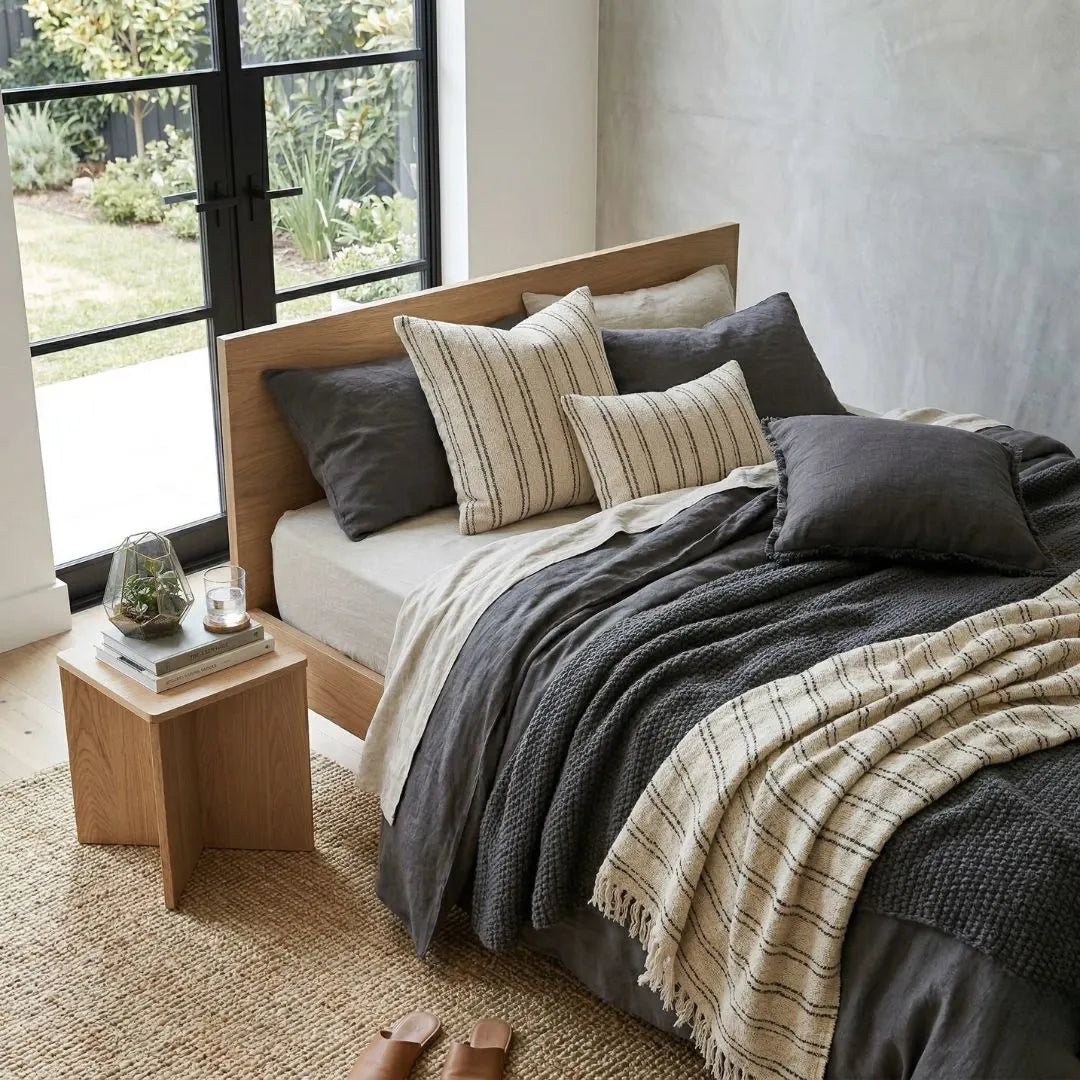 Bedroom with a wooden bed, pillows, and a nightstand with decor items.