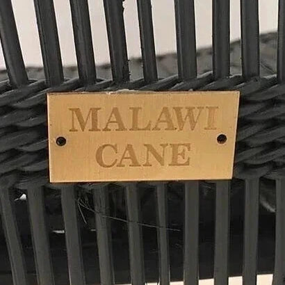 Black woven chair with a 'Malawi Cane' label on a blurred background