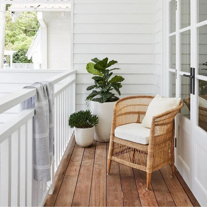 Balcony with wicker chair, potted plants, and white railing.