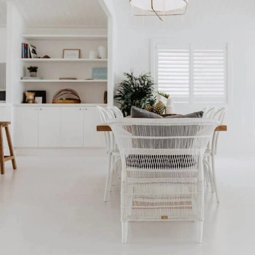 Modern kitchen with white cabinets, a dining area with wicker chairs, and a pendant light.
