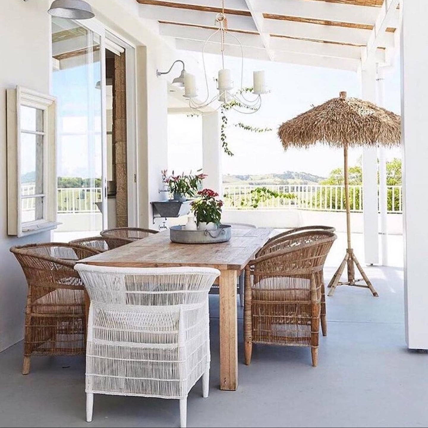 Outdoor patio with wooden table and wicker chairs under a white pergola.