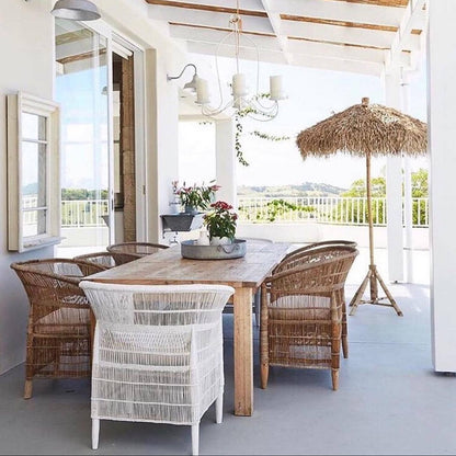 Outdoor patio with wooden table and wicker chairs under a white pergola.