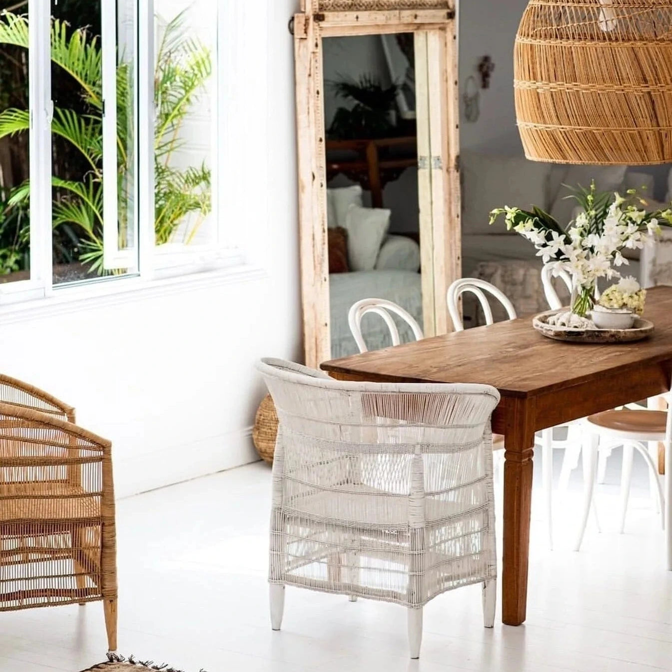 Dining room with wooden table, wicker chairs, and a large mirror.
