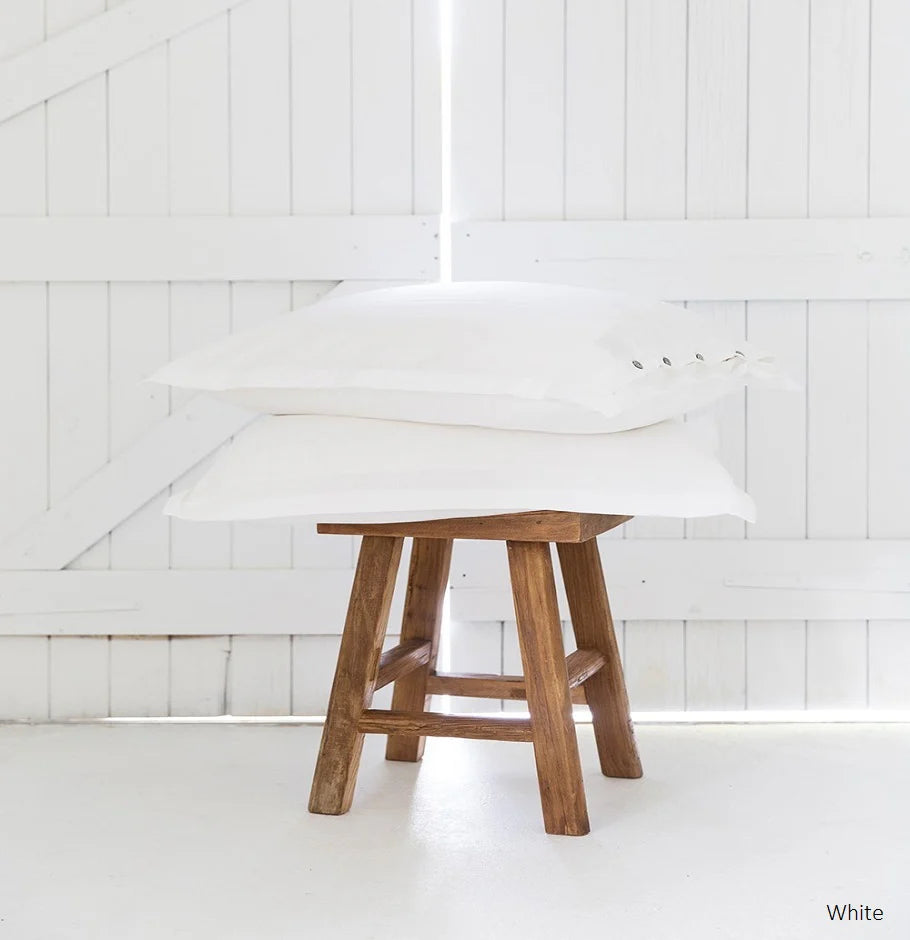 Wooden stool against a white paneled wall