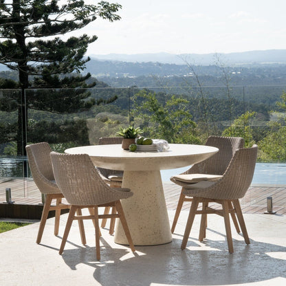 Round outdoor dining table with chairs on a patio with scenic view