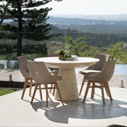 Outdoor dining area with a round table and chairs, overlooking a scenic landscape.