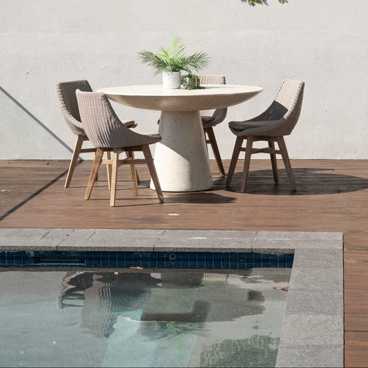 Outdoor dining set with a round table and chairs near a pool