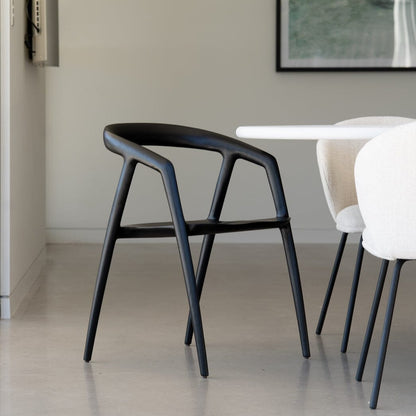 Modern black chair and white chair in a minimalistic room with a painting on the wall.
