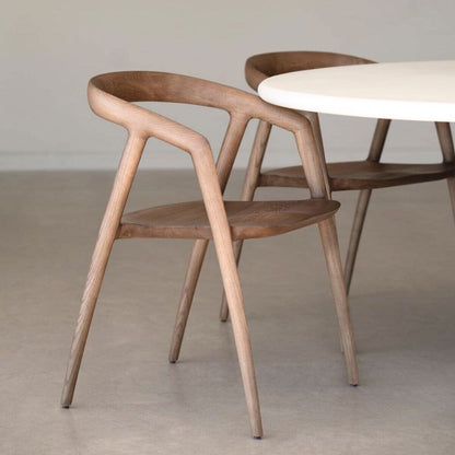 Wooden chair and round table in a minimalistic room with a neutral color palette.