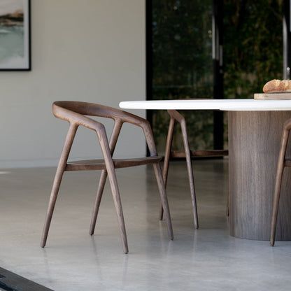 Dining area with wooden chair and round table in a modern interior setting.