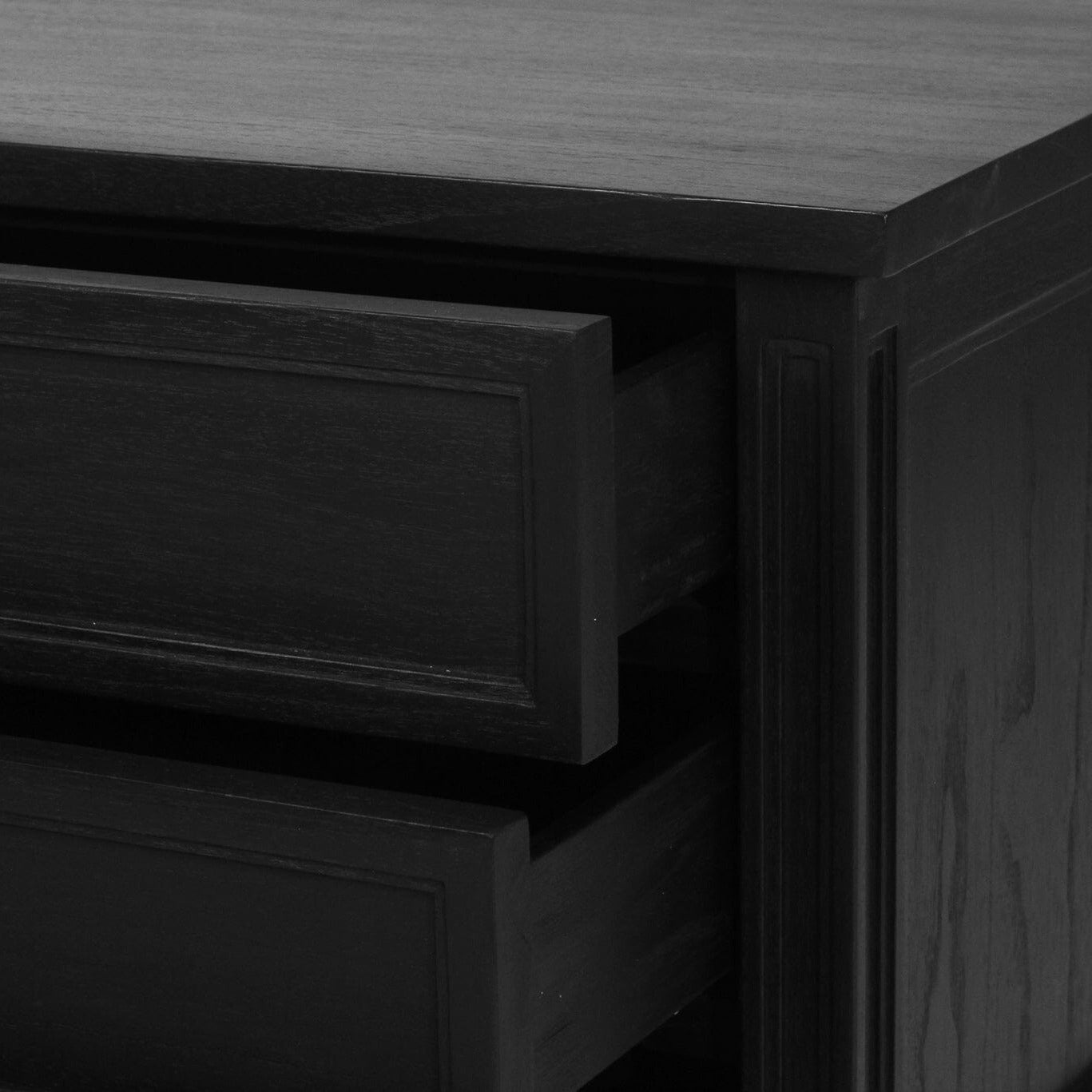 Close-up of a black wooden dresser with two partially open drawers and small round gold knobs.