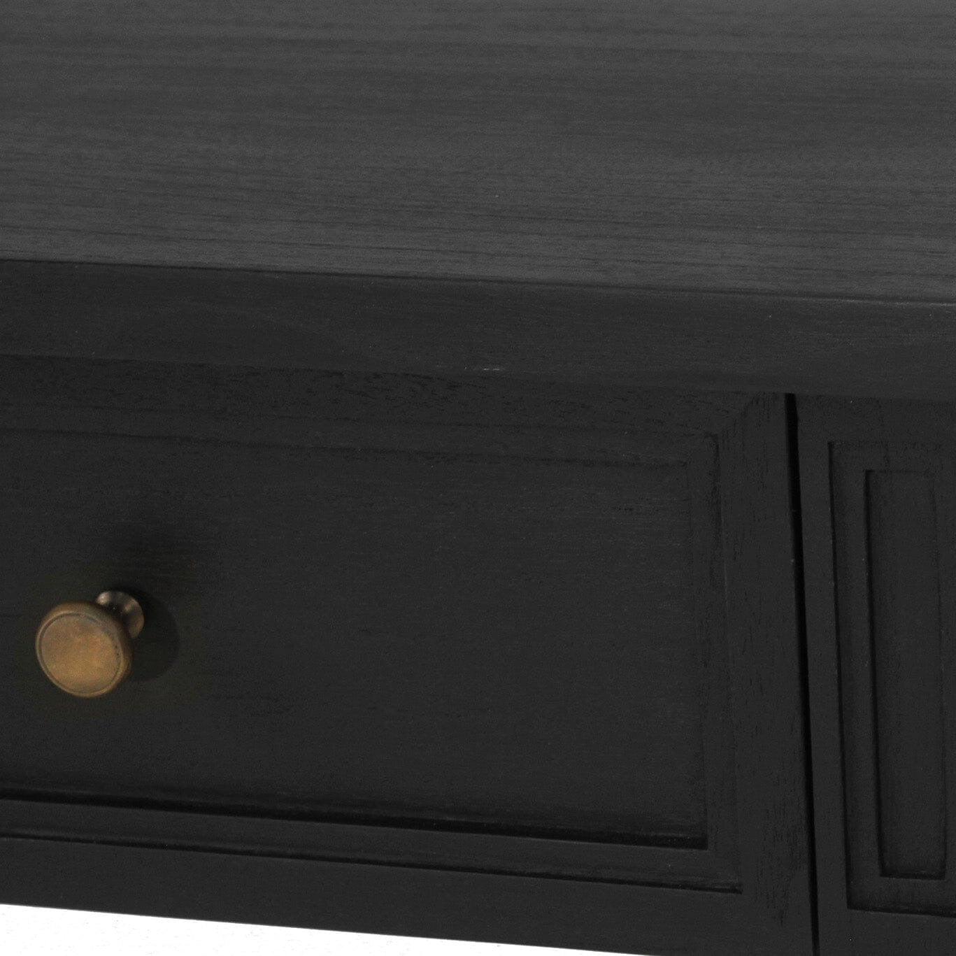 Close-up of a black wooden table or desk with a single drawer featuring a round brass knob, set against a white background.