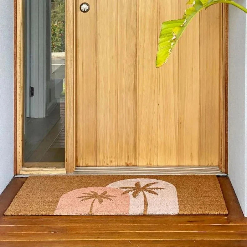 Doormat with palm tree design in front of a wooden door