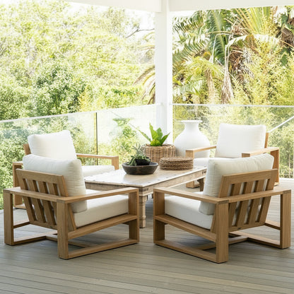 Outdoor patio set with wooden chairs and table on a deck with greenery in the background