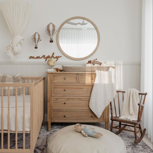 Nursery room with wooden crib, dresser, and rocking chair.