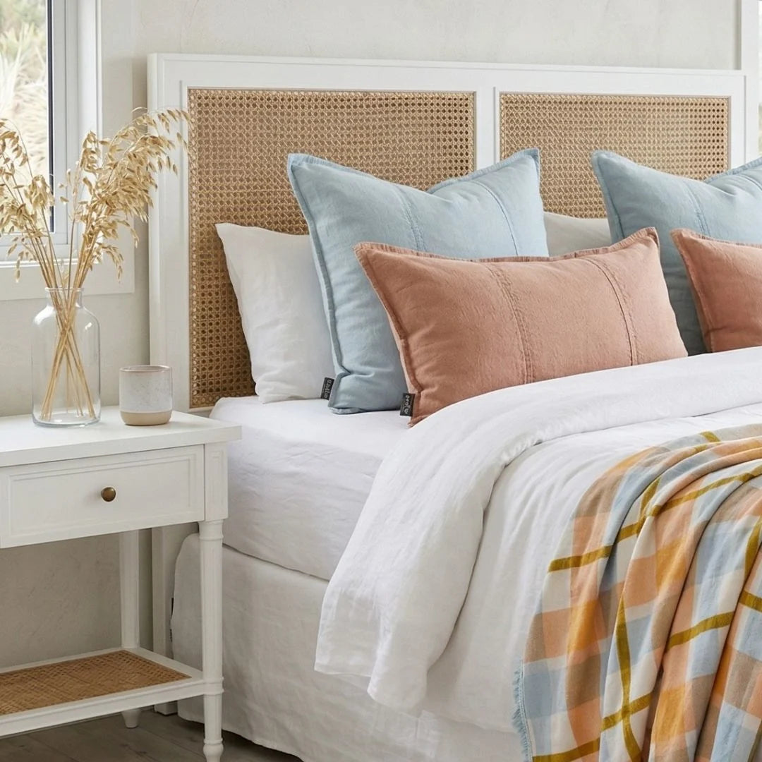 Bedroom with a bed featuring colorful pillows and a side table with decor items.