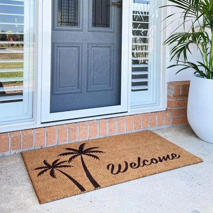 Coir doormat with palm tree design and 'Welcome' text on a porch with a blue door.