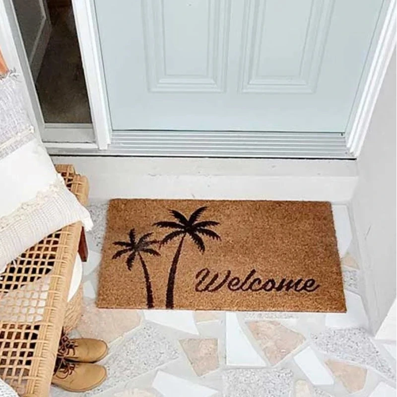 Coir doormat with palm tree design and 'Welcome' text on a tiled floor.