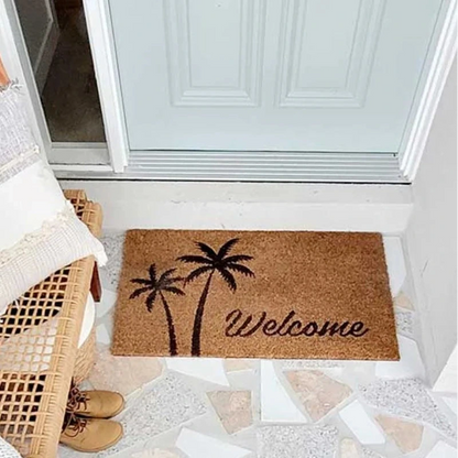 Coir doormat with palm tree design and 'Welcome' text on a tiled floor.