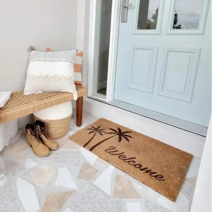 Front door with a 'Welcome' mat, wicker bench, and shoes on a light-colored floor.