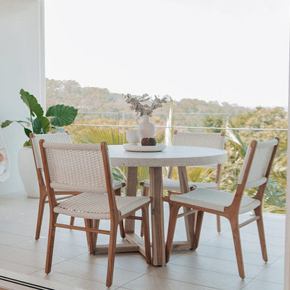 Round wooden table with terrazzo stone top,four matching chairs on a patio with a view of trees.