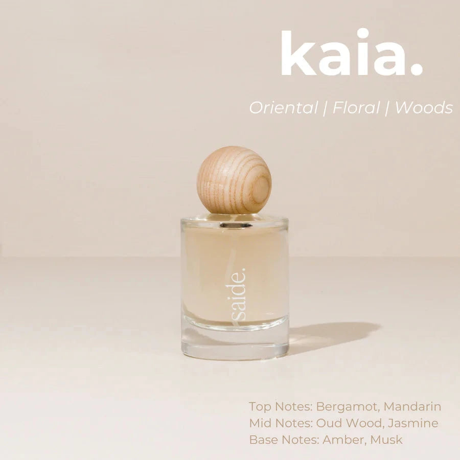 Perfume bottle with wooden cap on a beige background, featuring the brand 'kaia'.