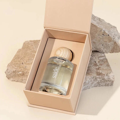 Glass bottle with wooden cap in a beige box on a stone surface