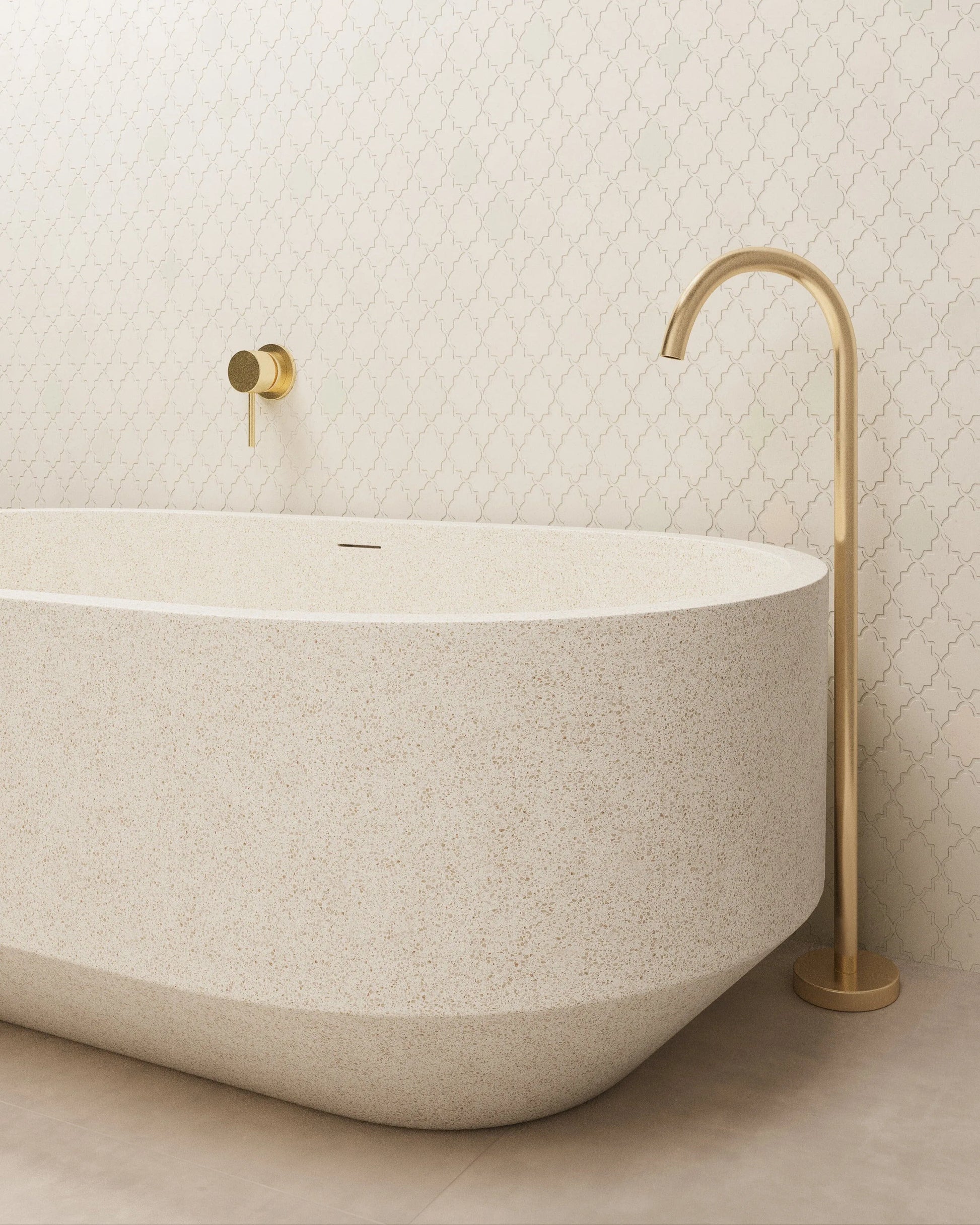 Beige freestanding bathtub with gold faucet against a light tiled wall.