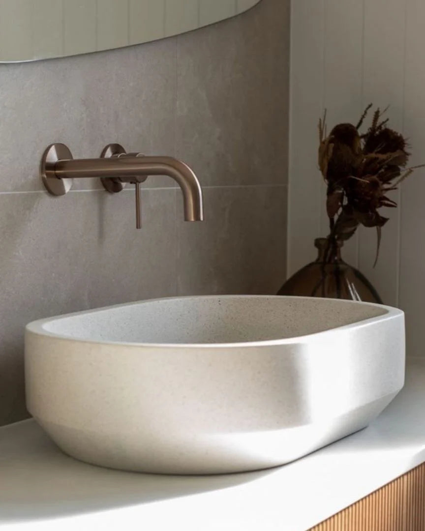 Bathroom sink with bronze faucet and decorative vase in the background