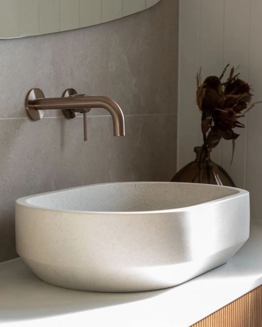 Bathroom sink with bronze faucet and decorative vase in the background