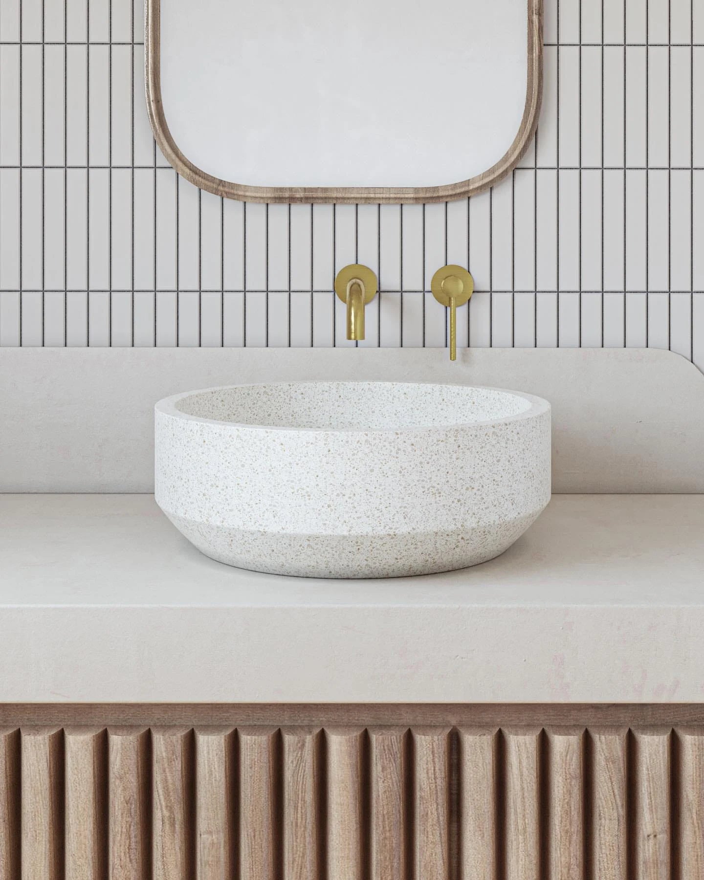 Bathroom vanity with a stone sink, gold faucet, and mirror.