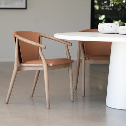 Modern dining area with a white round table and wooden chairs. Featuring the Elio Round Microcement Dining Table – Seashell Finish from Sun Republic